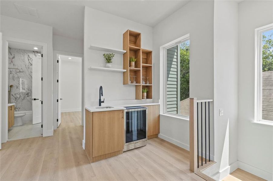 Wet-Bar featuring sink, kitchen peninsula, light hardwood / wood-style flooring, and beverage cooler