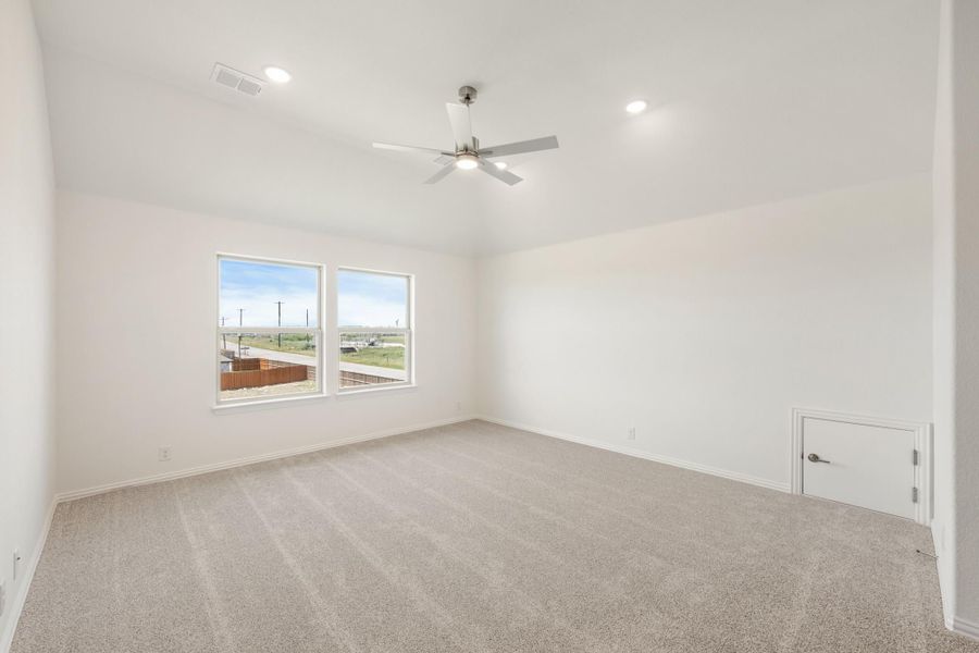Empty bedroom with beige carpet, ceiling fan, recessed lighting, and two windows with outdoor views Empty bedroom with beige carpet, ceiling fan, recessed lighting, and two windows with outdoor views