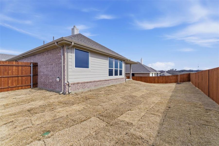 Rear view of property featuring a fenced backyard, a chimney, and brick siding