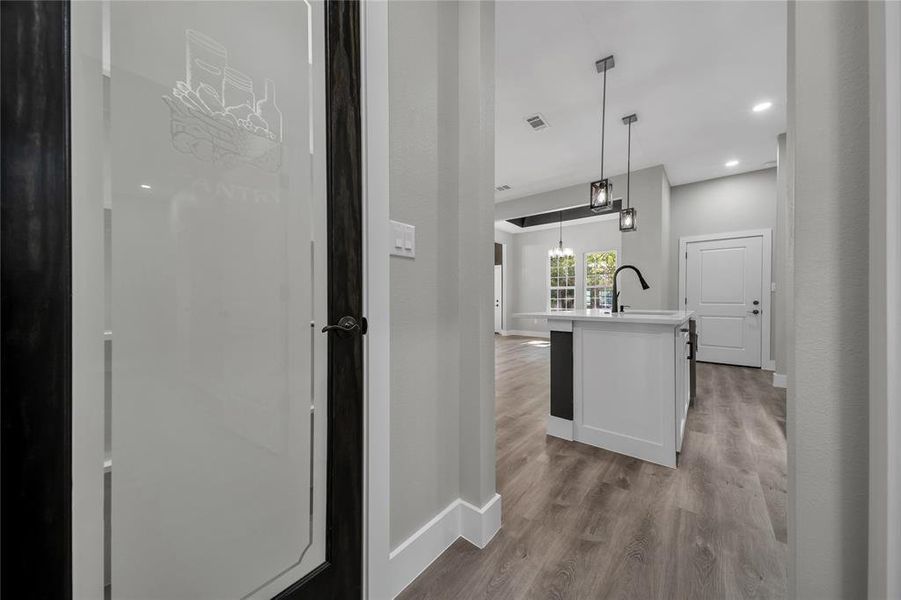 Kitchen with a center island with sink, hanging light fixtures, sink, and light wood-type flooring