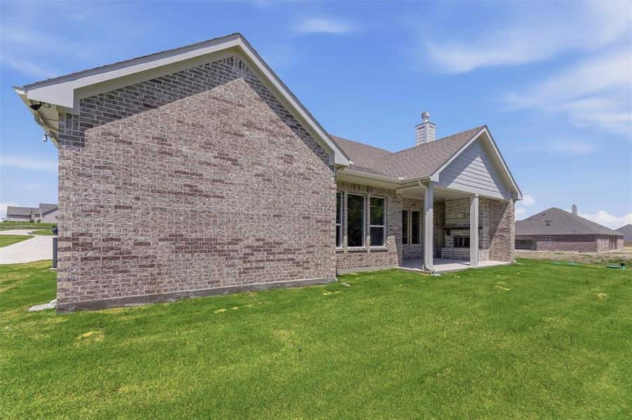 Brick exterior with a covered patio, featuring an outdoor fireplace