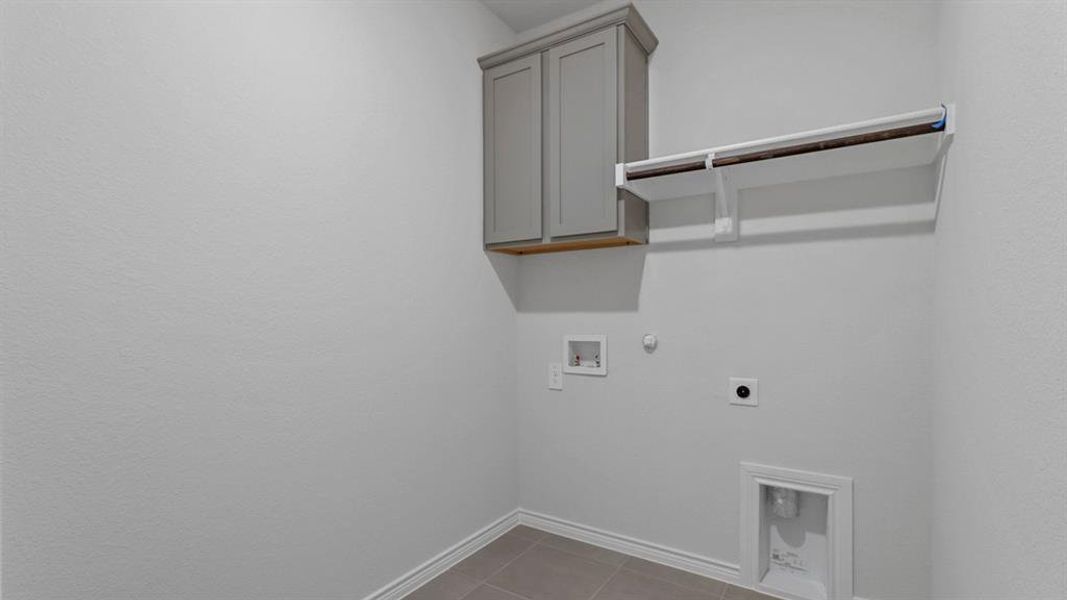 Laundry room with hookup for a gas dryer, cabinet space, light tile patterned floors, electric dryer hookup, and hookup for a washing machine