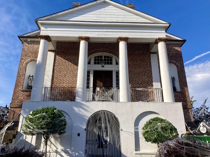 View of front of house featuring brick siding and a balcony