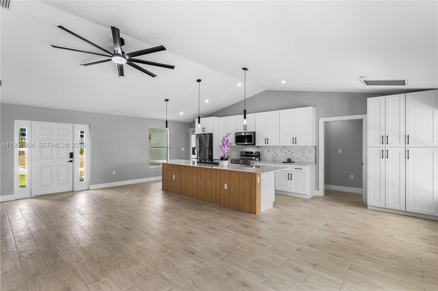 The dining area is enhanced by vaulted ceilings, recessed lighting, and a large window overlooking the outdoor space, complemented by custom built-in cabinetry for added storage and upscale appeal.