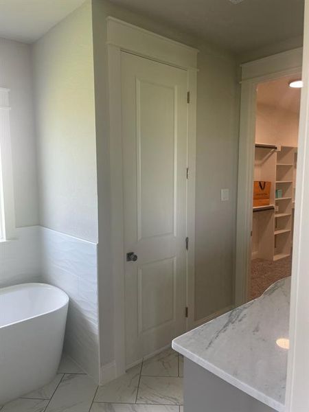 Bathroom featuring a soaking tub, marble finish flooring, and a spacious closet Bathroom featuring a soaking tub, marble finish flooring, and a spacious closet