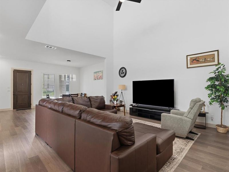 Spacious living area featuring high vaulted ceilings, wood-finish flooring, and a ceiling fan
