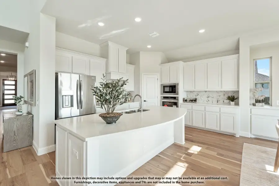 White kitchen with large curved island, stainless steel appliances, marble backsplash, and light hardwood floors White kitchen with large curved island, stainless steel appliances, marble backsplash, and light hardwood floors
