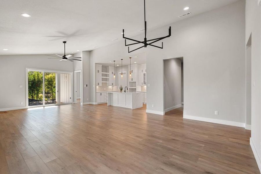 Kitchen with a kitchen island with sink, white cabinets, light stone countertops, decorative light fixtures, and backsplash Kitchen with a kitchen island with sink, white cabinets, light stone countertops, decorative light fixtures, and backsplash