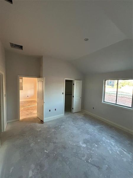 Unfurnished bedroom with baseboards and lofted ceiling