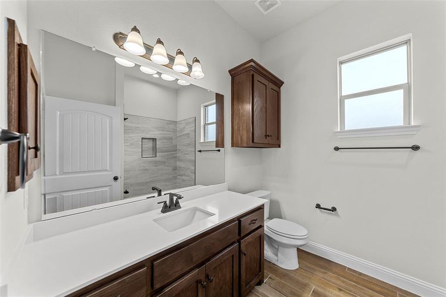 Bathroom with toilet, vanity, and tiled shower