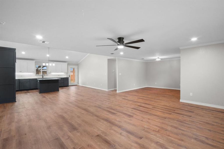 Unfurnished living room with wood-type flooring, ceiling fan, crown molding, and sink Unfurnished living room with wood-type flooring, ceiling fan, crown molding, and sink