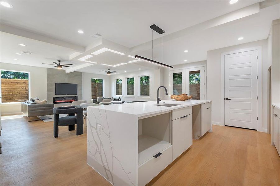 Kitchen with white cabinetry, light wood-type flooring, ceiling fan, decorative light fixtures, and sink