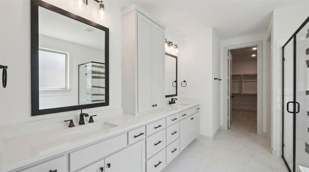Bathroom featuring a dual vanity with white cabinetry and integrated sinks