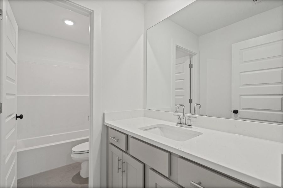 Vanity with integrated sink, stone countertop, chrome faucet, and expansive mirror