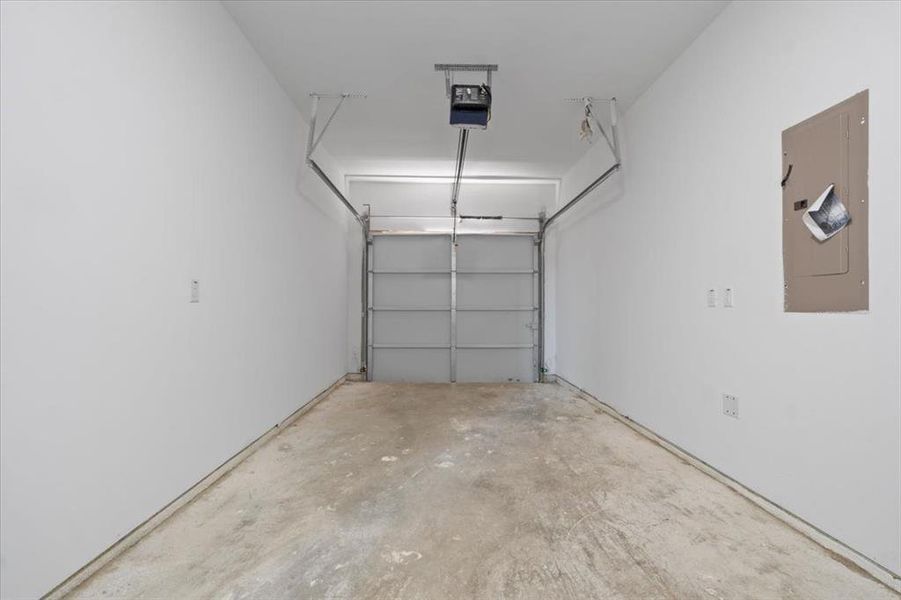 Garage featuring electric panel and a garage door opener