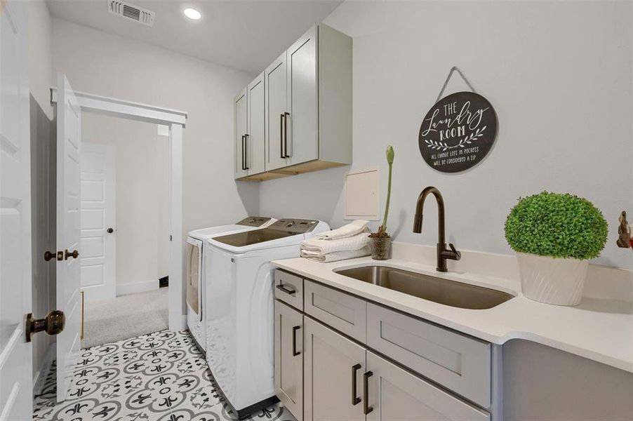 Washroom with sink, cabinets, and washing machine and dryer