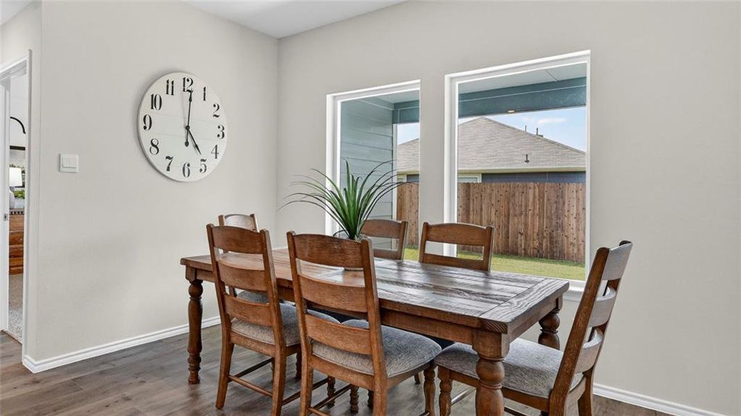 Bright room featuring wood-finish flooring, two large windows, light gray wall paint, and white baseboards Bright room featuring wood-finish flooring, two large windows, light gray wall paint, and white baseboards