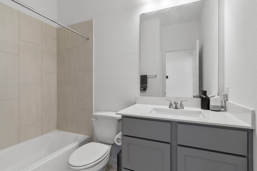 Bathroom featuring a textured wall, vanity, and shower / bath combination