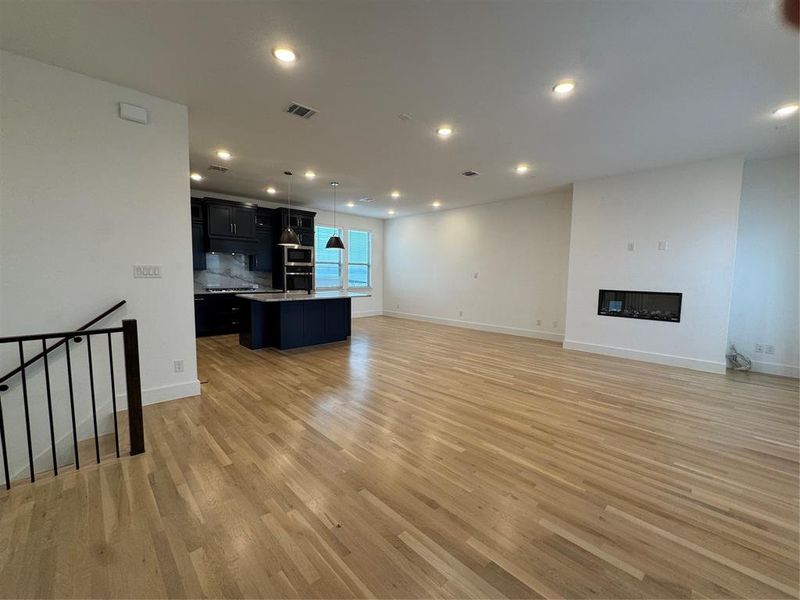 Unfurnished living room with recessed lighting, visible vents, light wood-style floors, and a glass covered fireplace