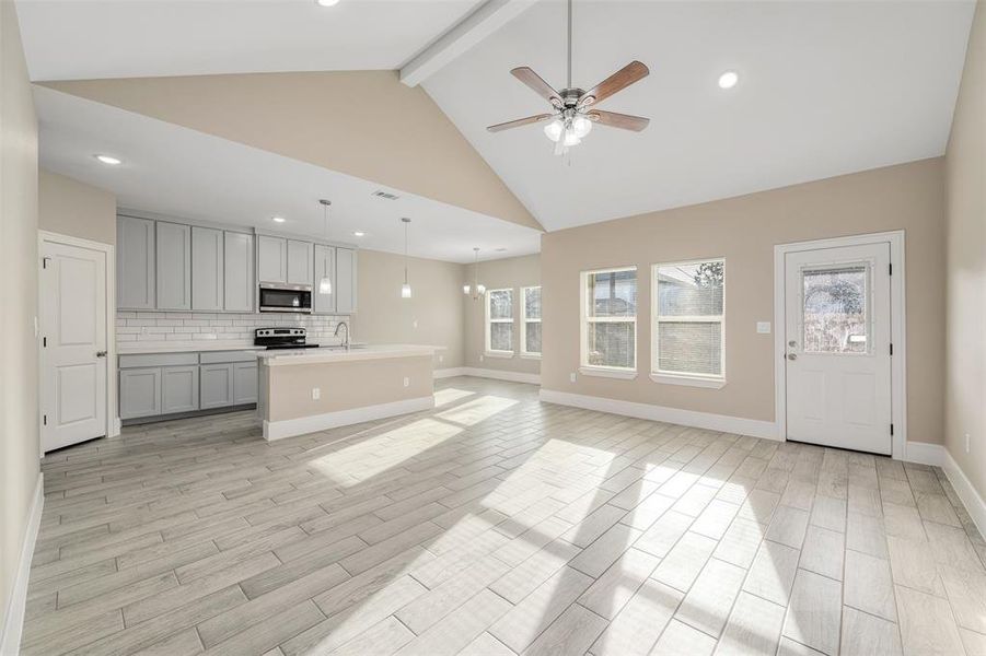 Unfurnished living room with beam ceiling, light hardwood / wood-style flooring, and plenty of natural light