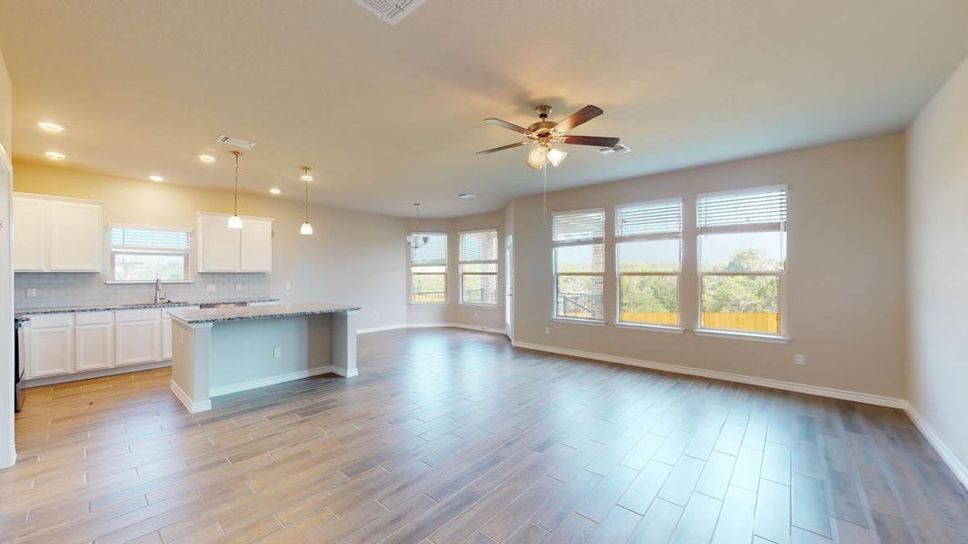 Kitchen featuring a kitchen island, white cabinets, hanging light fixtures, open floor plan, and light wood-type flooring Kitchen featuring a kitchen island, white cabinets, hanging light fixtures, open floor plan, and light wood-type flooring