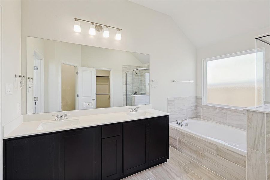 Bathroom featuring vanity, lofted ceiling, and plus walk in shower