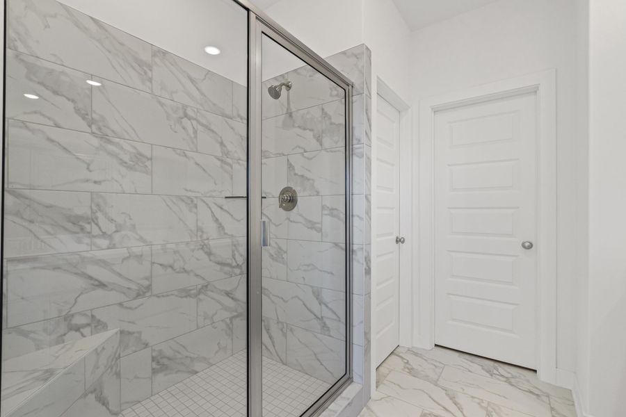 Bathroom featuring light marble finish flooring and a marble finish shower