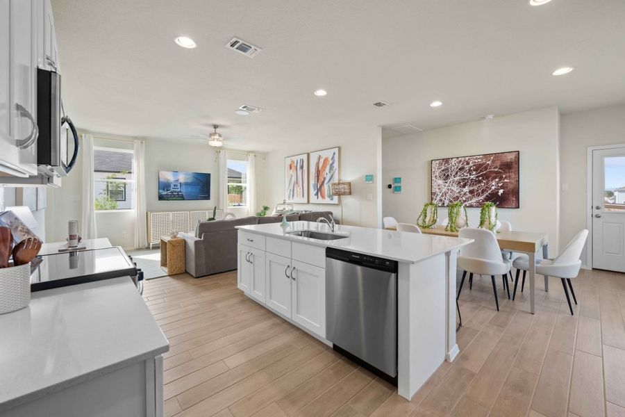 An interior image of a kitchen with white marble counter top and island, vinyl flooring, white cabinets, and steel refrigerator and dishwashers and a black and steel stove. An interior image of a kitchen with white marble counter top and island, vinyl flooring, white cabinets, and steel refrigerator and dishwashers and a black and steel stove.