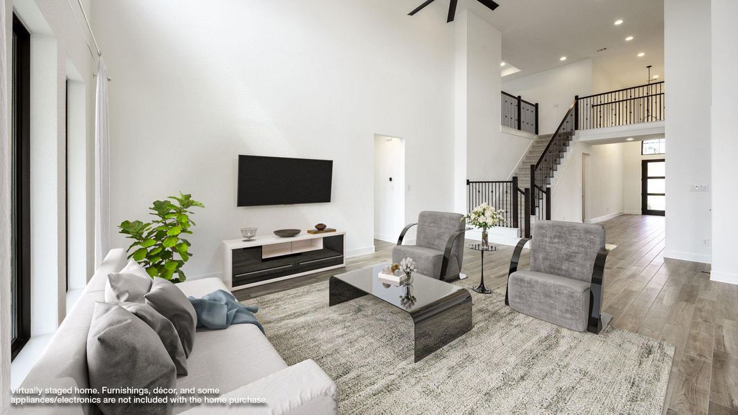 Living room with wood finished floors, a towering ceiling, stairs, recessed lighting, and ceiling fan