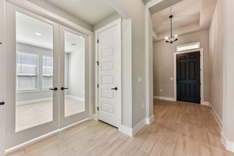 Foyer with french doors, light wood-style floors, a chandelier, and a tray ceiling