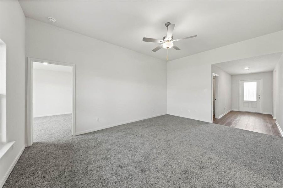 Empty room featuring ceiling fan, baseboards, and dark colored carpet