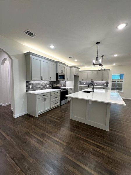 Kitchen featuring sink, hanging light fixtures, a center island with sink, dark hardwood / wood-style flooring, and stainless steel appliances