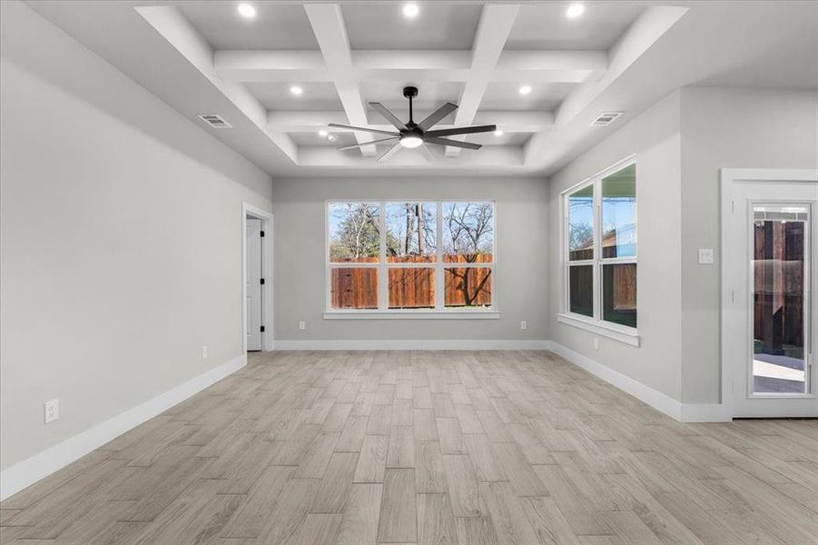 Spare room featuring baseboards, coffered ceiling, visible vents, and light wood-style floors