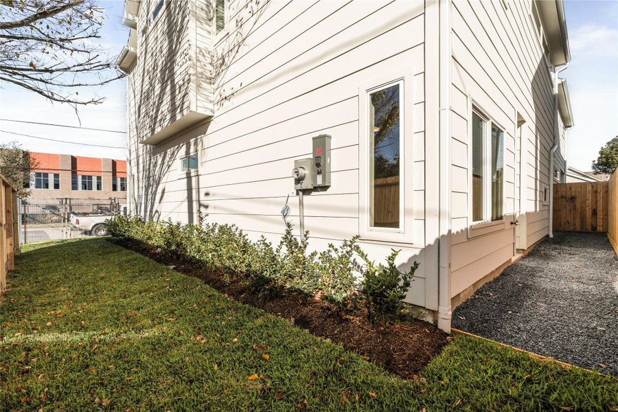 A side yard that wraps into the rear of the home, complete with a full French drain system — a detail typically upgraded, here included as standard for long-term drainage and peace of mind.