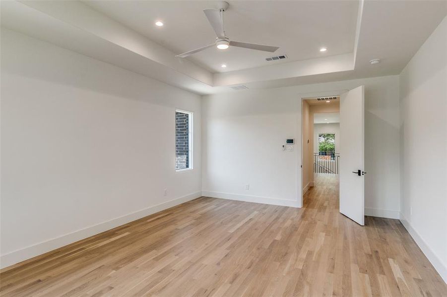 Unfurnished room with a tray ceiling, light wood-style floors, recessed lighting, and a ceiling fan Unfurnished room with a tray ceiling, light wood-style floors, recessed lighting, and a ceiling fan
