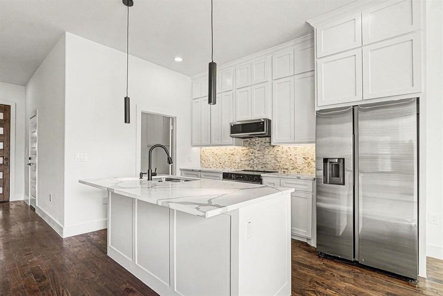 The kitchen island has a pull-down sprayer faucet and dual stainless sinks.  The granite countertop serves as a breakfast bar, complemented by upscaled dual pendant lighting.