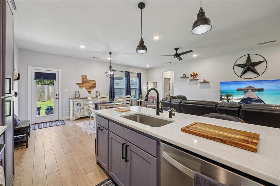 Kitchen featuring recessed lighting, light stone countertops, open floor plan, dishwasher, and decorative light fixtures Kitchen featuring recessed lighting, light stone countertops, open floor plan, dishwasher, and decorative light fixtures