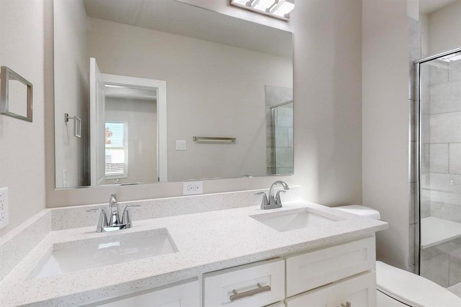 Bathroom featuring vanity, a shower with shower door, and toilet