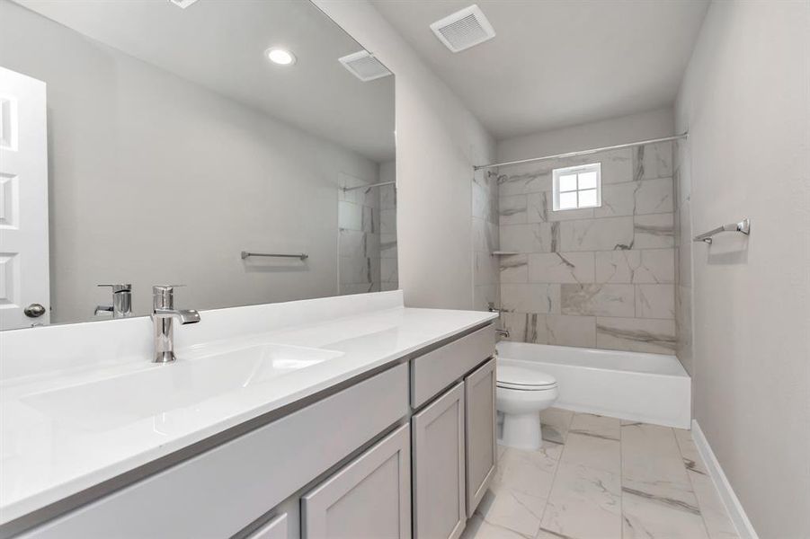 Experience sophistication in the secondary bathroom, where tile flooring complements a bath/shower combo with tile surround. Light wood cabinets complete with a beautiful light countertop, enhances the space for a truly inviting ambiance. Sample photo of completed home with similar floor plan. As built color and selections may vary.