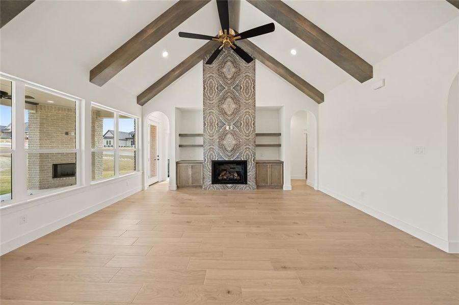 Spacious living area featuring a vaulted ceiling with exposed wood beams and a contemporary ceiling fan