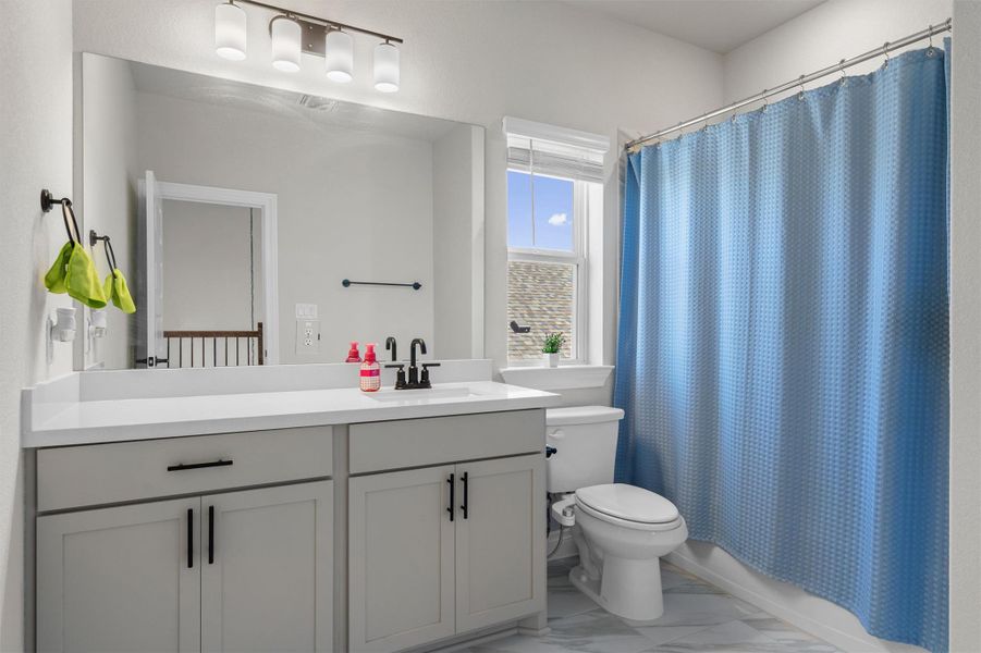Natural light from a classic window illuminates a modern vanity and clean tiled flooring.