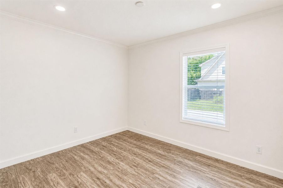 Recessed lighting illuminates this room, showcasing the natural wood-look flooring and crown molding. Recessed lighting illuminates this room, showcasing the natural wood-look flooring and crown molding.