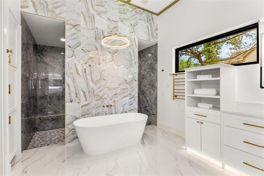 Freestanding soaking tub centered on a feature wall with full-height marble-look tile