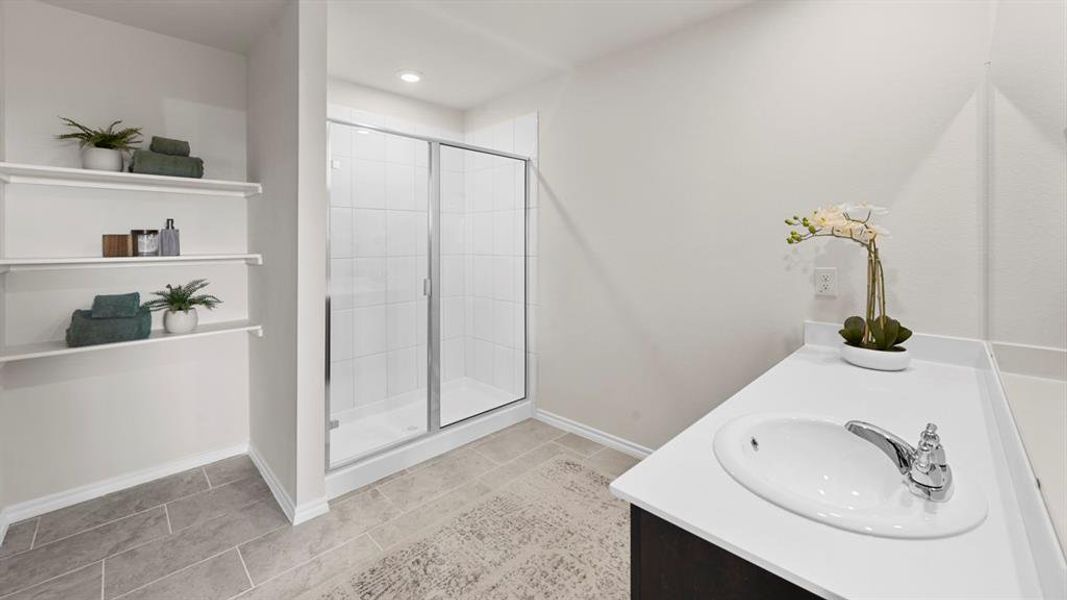 The bathroom features a shower with sliding glass doors, a vanity with an integrated sink and chrome faucet, and open shelving for storage