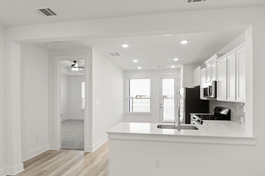 Kitchen with light stone countertops, white cabinetry, stainless steel appliances, light wood-style flooring, and recessed lighting