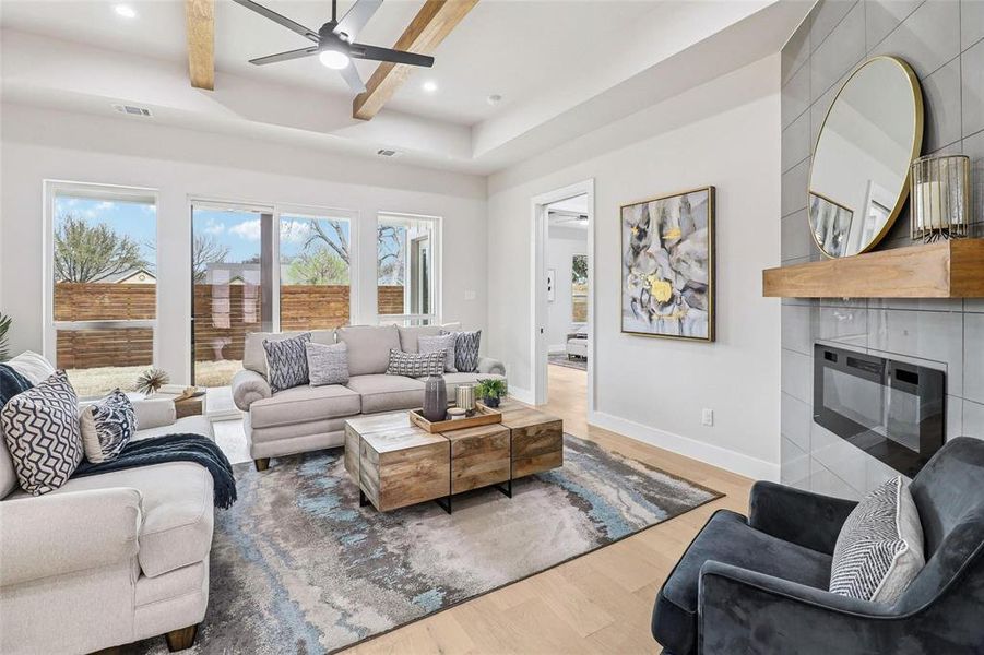 The living area features a high ceiling with exposed wooden beams, a ceiling fan, and light wood flooring
