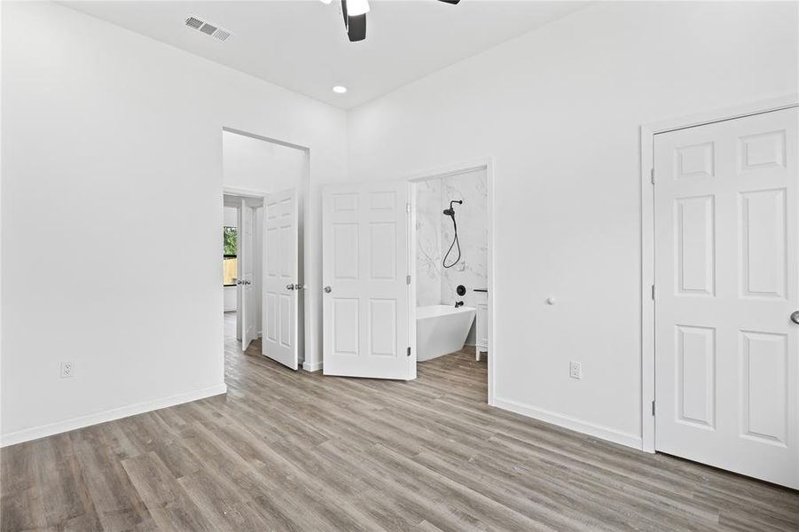 Unfurnished bedroom featuring light wood-type flooring, ceiling fan, and ensuite bath