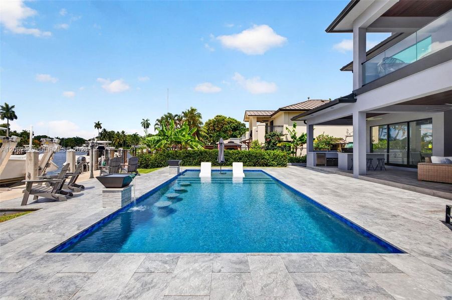 Salt chlorinated pool w/ water features, LED color changing light, sun shelf with umbrella hole and in water stools. Stone decking surrounds the pool