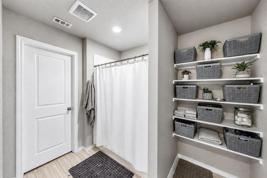 Bathroom featuring a shower with a white curtain, light wood-finish flooring, recessed lighting, and an expansive built-in shelving unit