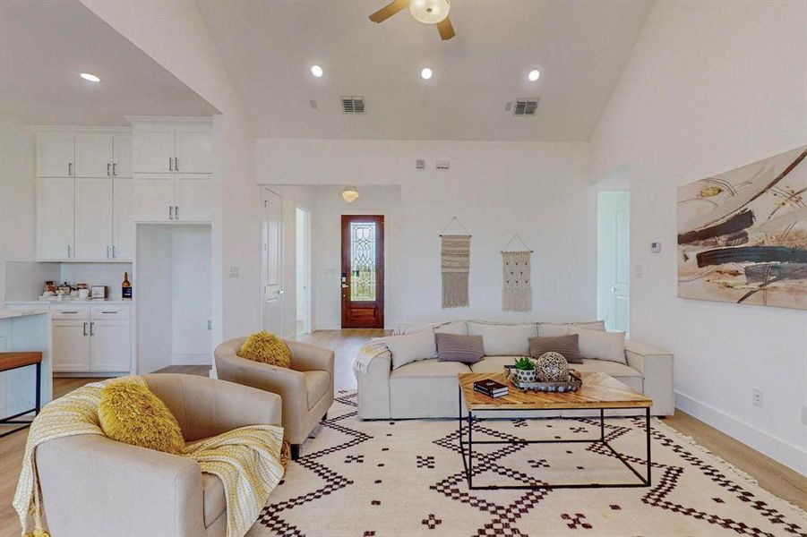 Living room featuring light wood-type flooring, high vaulted ceiling, and ceiling fan